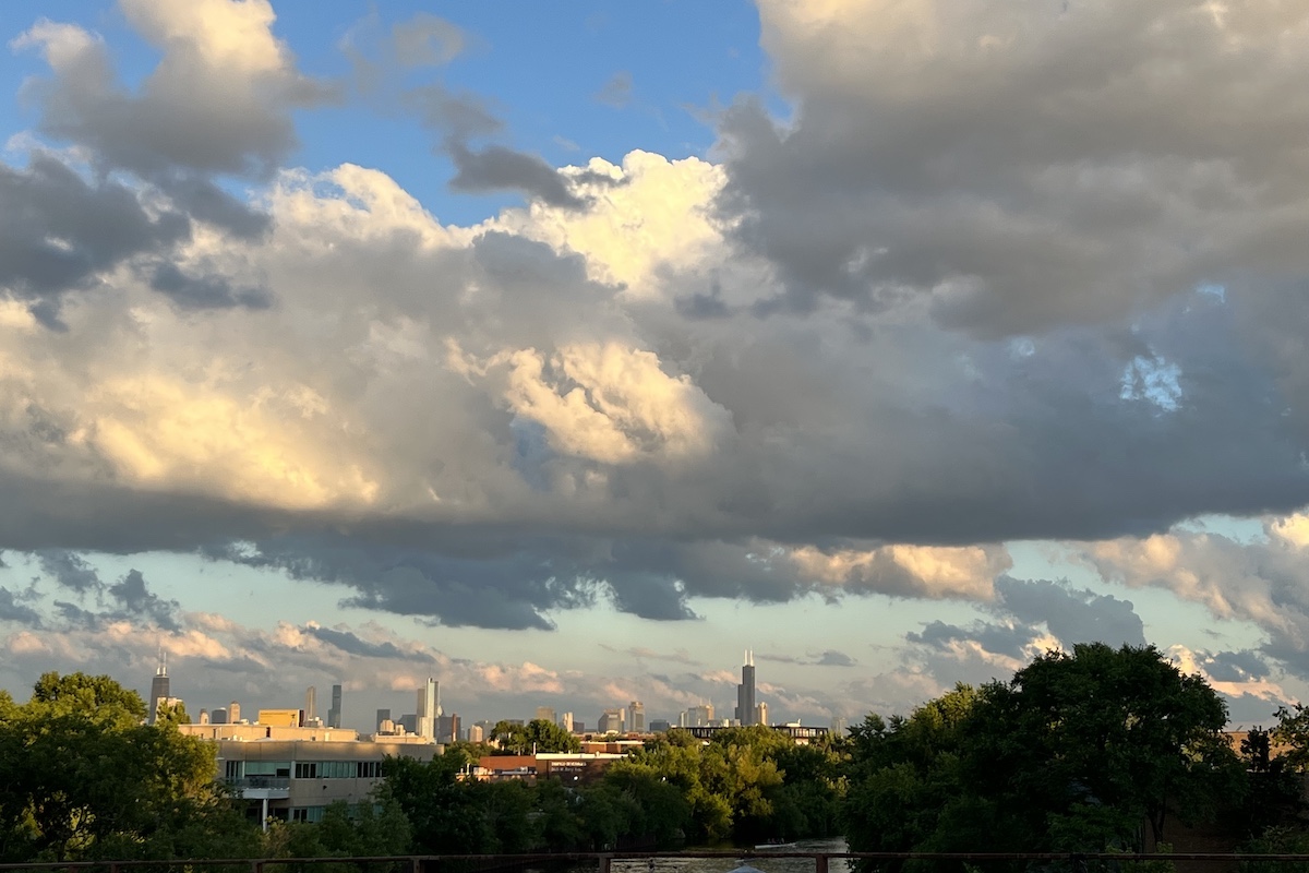 A dramatic partly cloudy sky over the Chicago river at sunset. In the background is the Chicago city skyline.