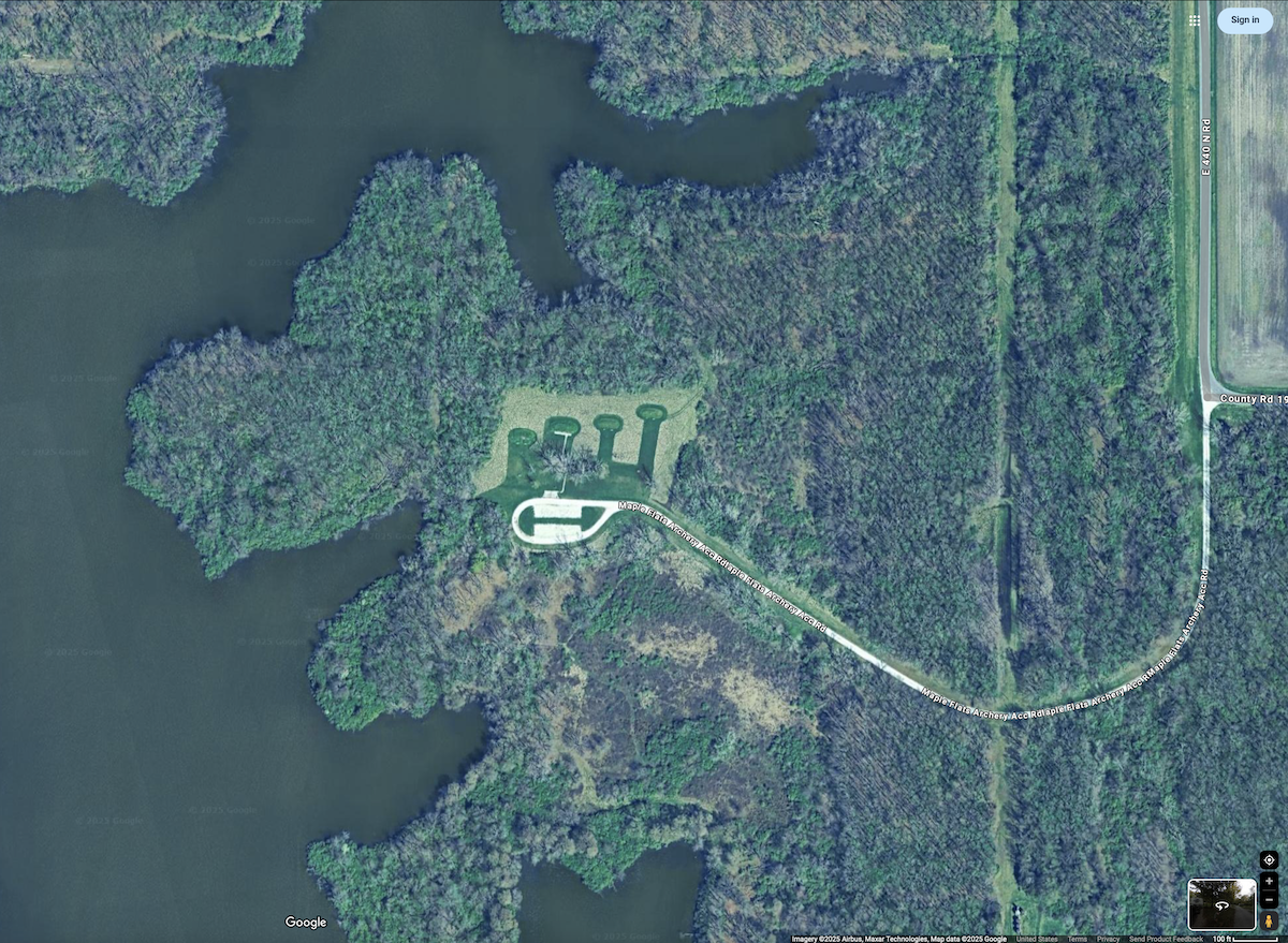 An aerial view of an archery range in a State Park. A lake is to the left of the photo and the archery range is surrounded by a woodland.
