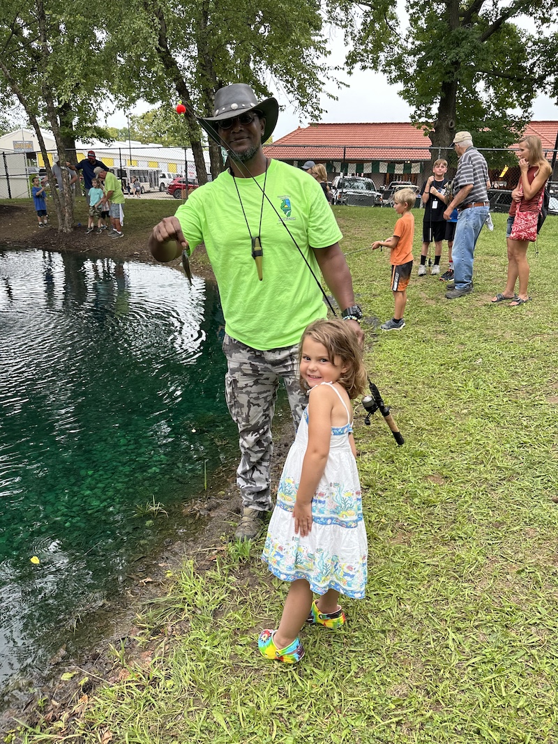 Eliha Perez teaches a young girl how to fish. They are posing with her first catch.