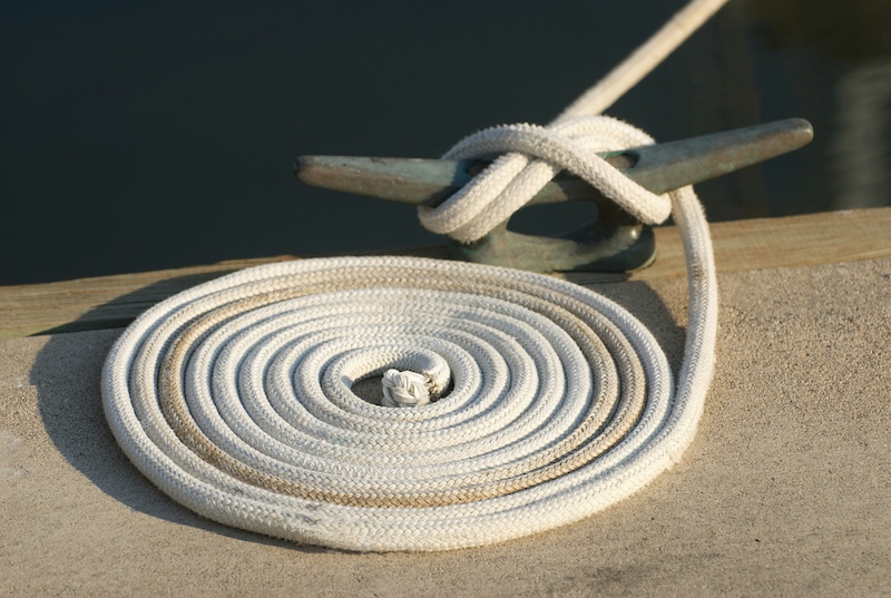 A close-up of a rope securing a boat tied to a cleat on a dock.