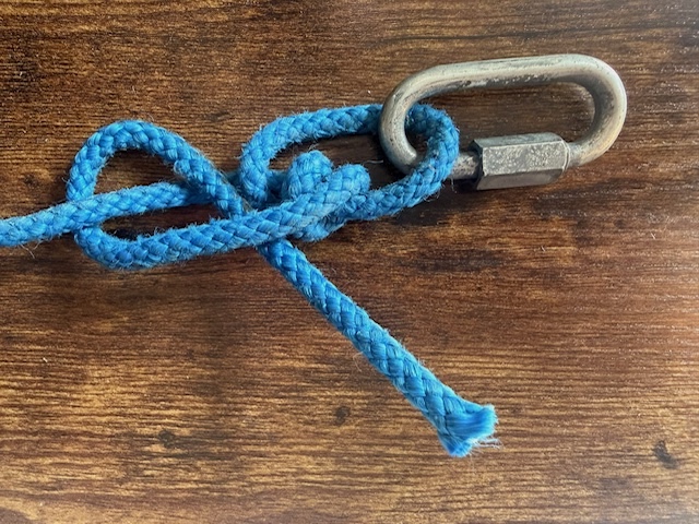 A close-up of a blue rope tied to a metal ring.