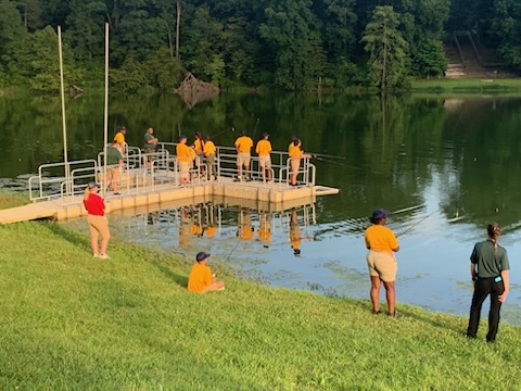 A group of teenagers at a fishing clinic fish from a dock over the lake. Photo by Scott Isringhausen
